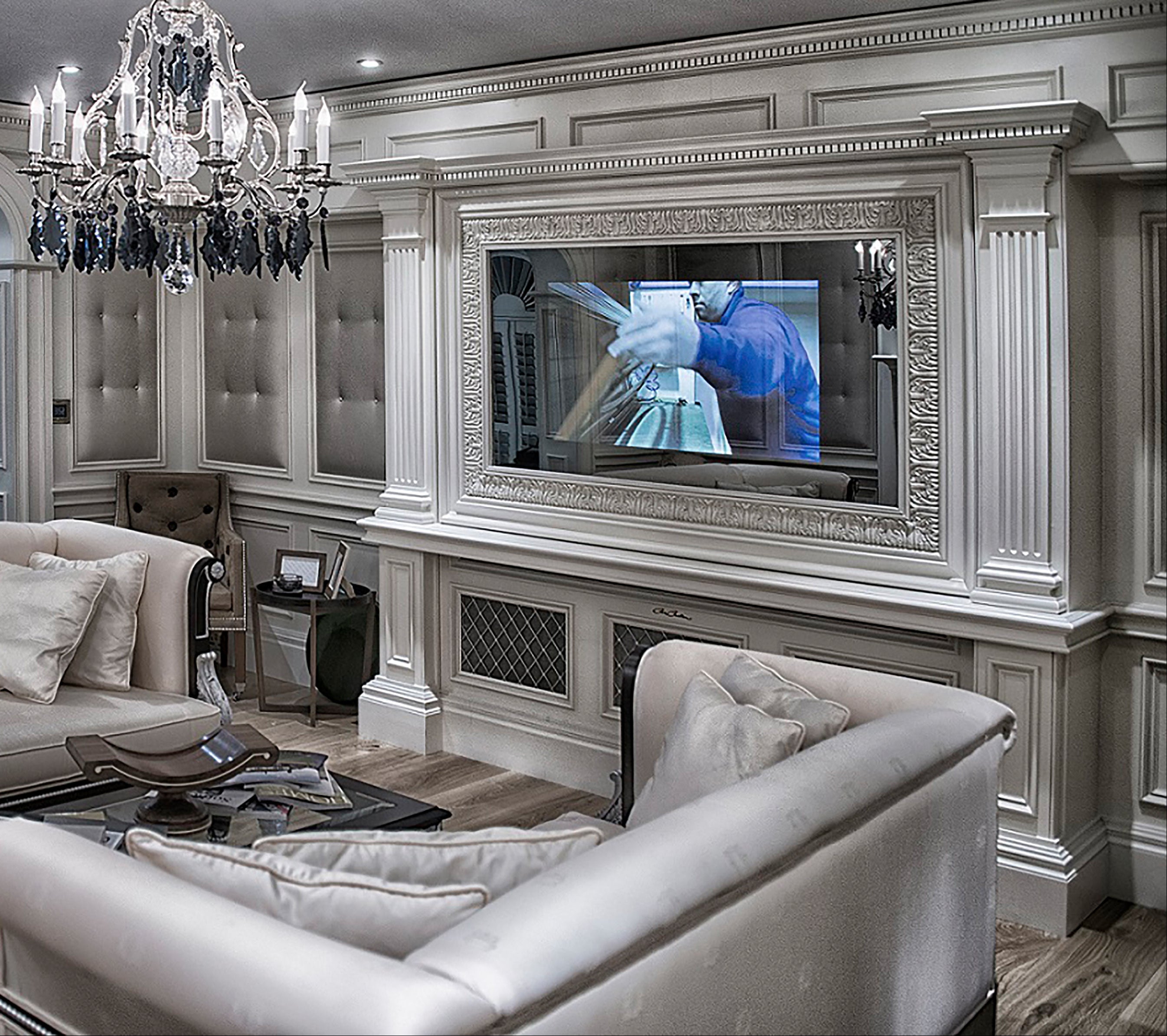 Luxurious living room with gray sofa, chandelier, and television mirror.